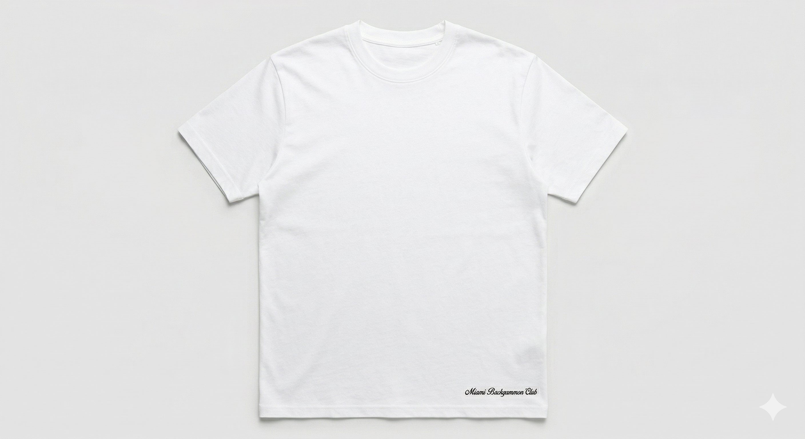 Flat lay of the white Signature Script Tee with Miami Backgammon Club script logo printed at the bottom right hem