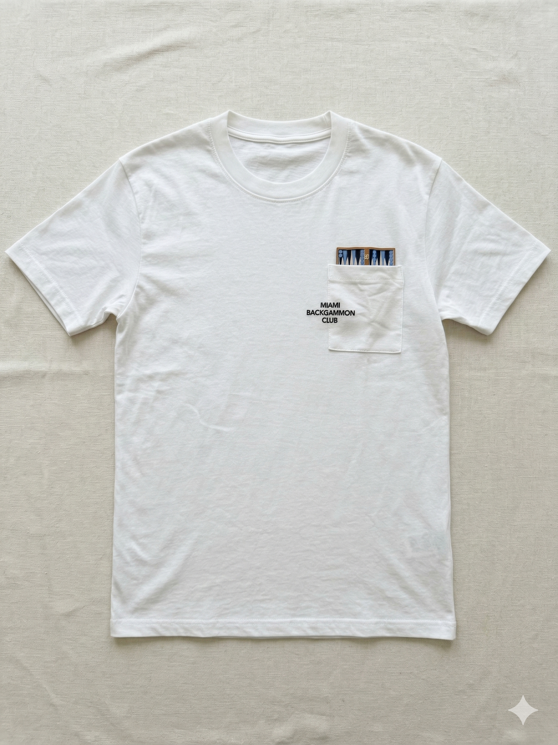 Flat lay of the Classic White Pocket Tee with backgammon board graphic and Miami Backgammon Club logo printed on the chest pocket