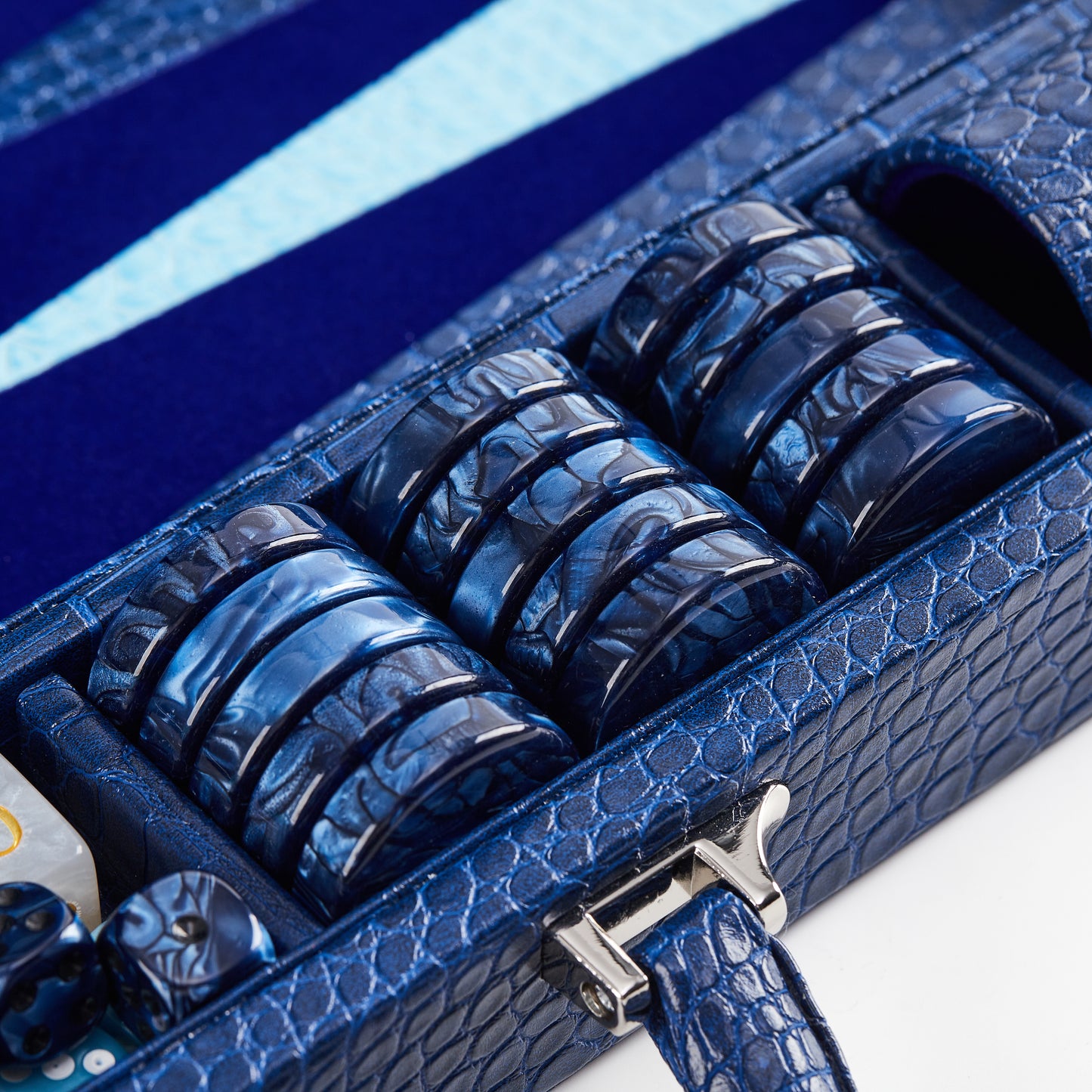 Close-up of stacked navy crocodile-embossed checkers and silver clasp on the Midnight Navy backgammon case