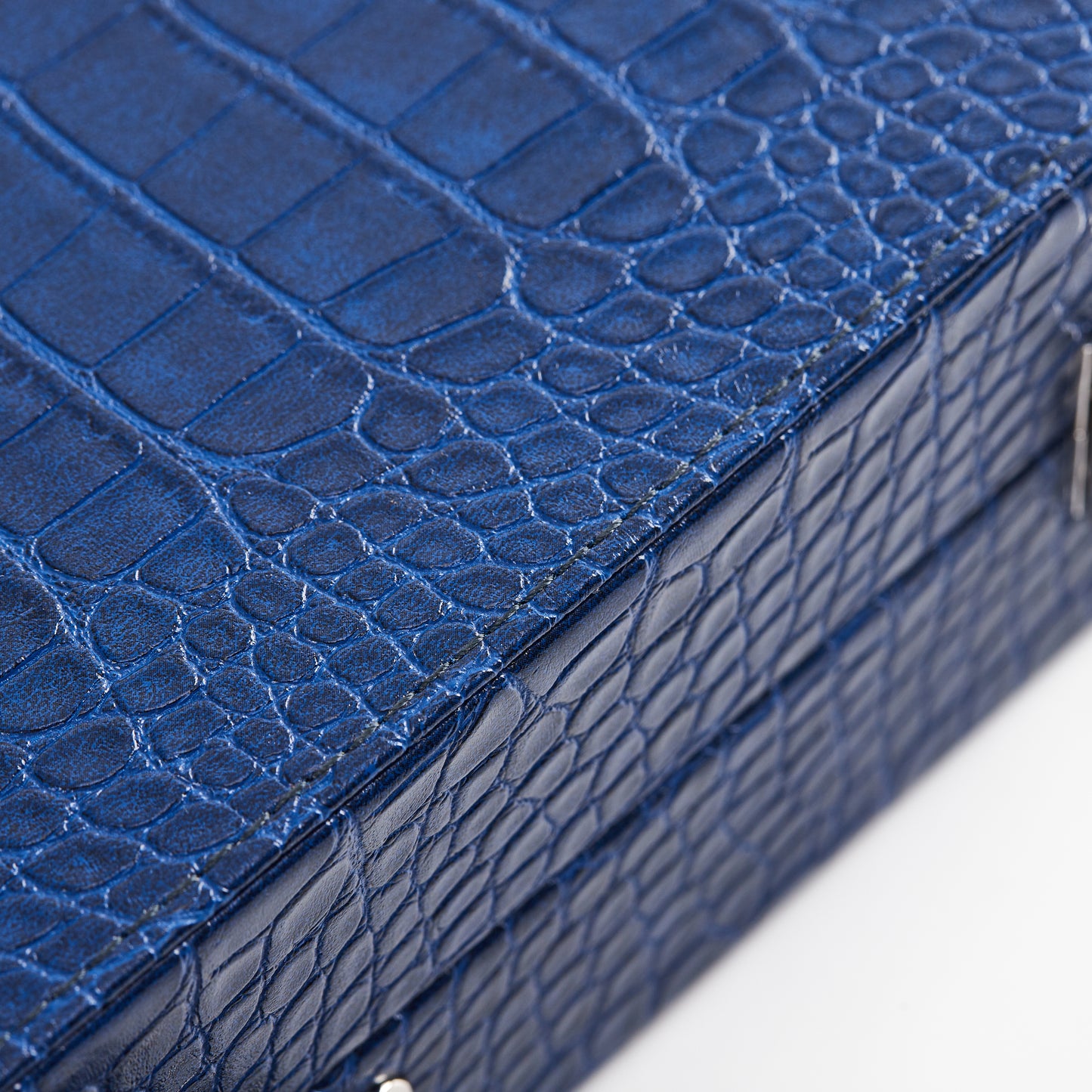 Macro texture close-up of the Midnight Navy crocodile-embossed leather corner detail on the backgammon case