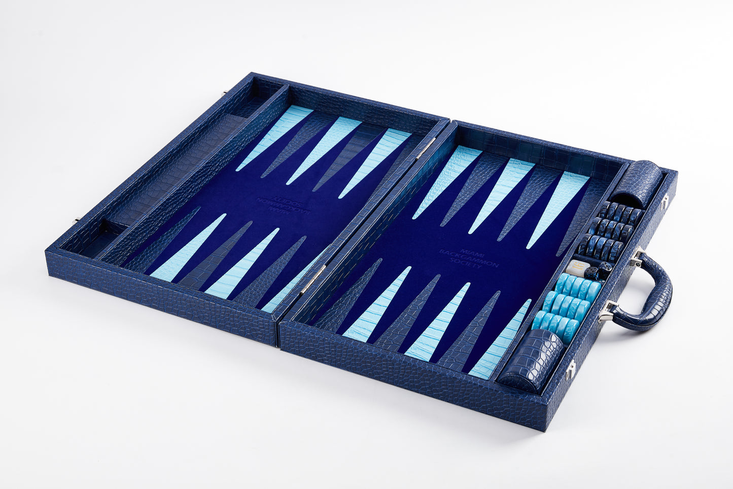 Elevated angled view of the Midnight Navy backgammon board laid flat and open, empty playing field with checkers stacked at the side