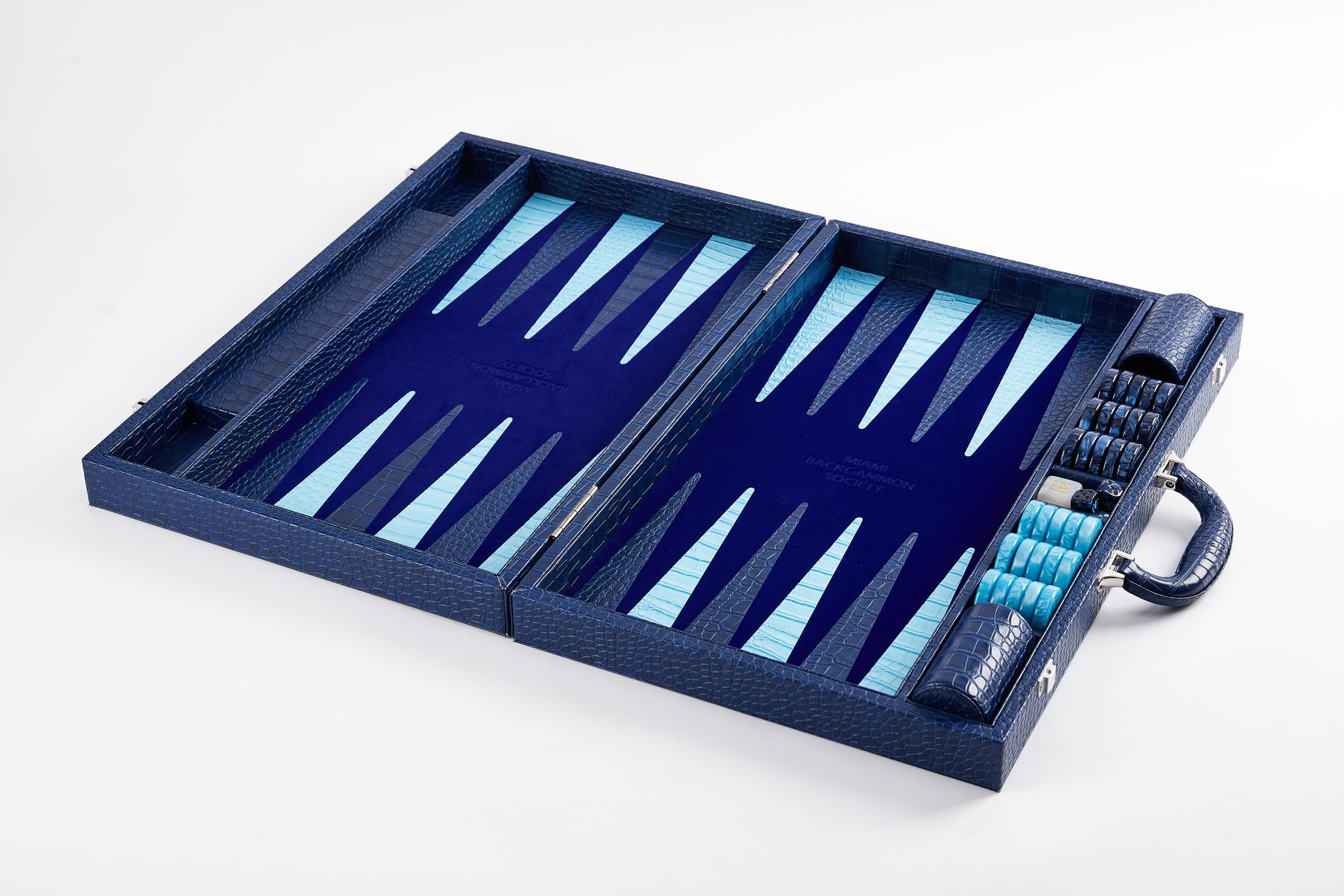 Elevated angled view of the Midnight Navy backgammon board laid flat and open, empty playing field with checkers stacked at the side
