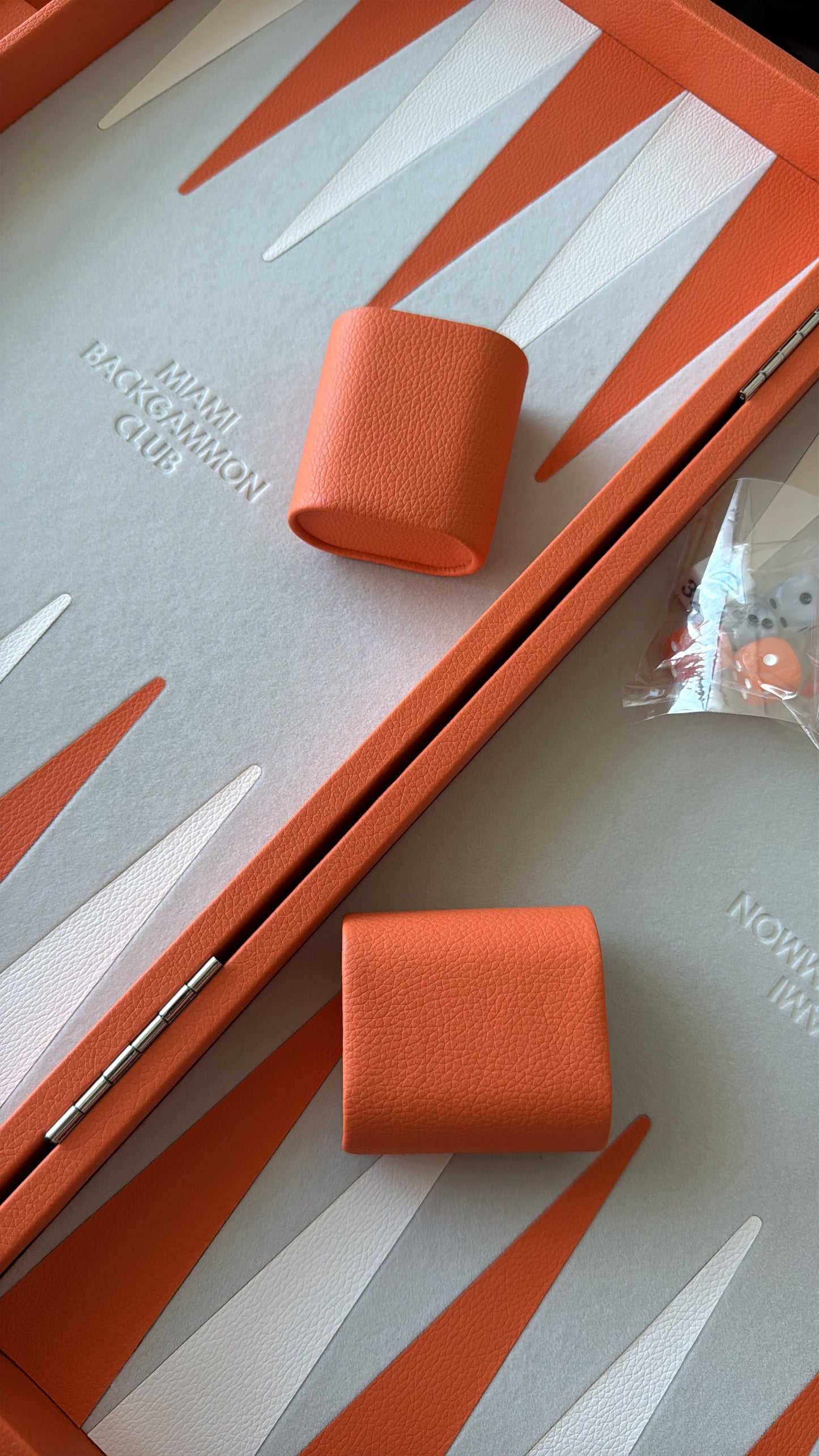 Orange Miami Backgammon Club board with dice cups and game pieces on playing surface.