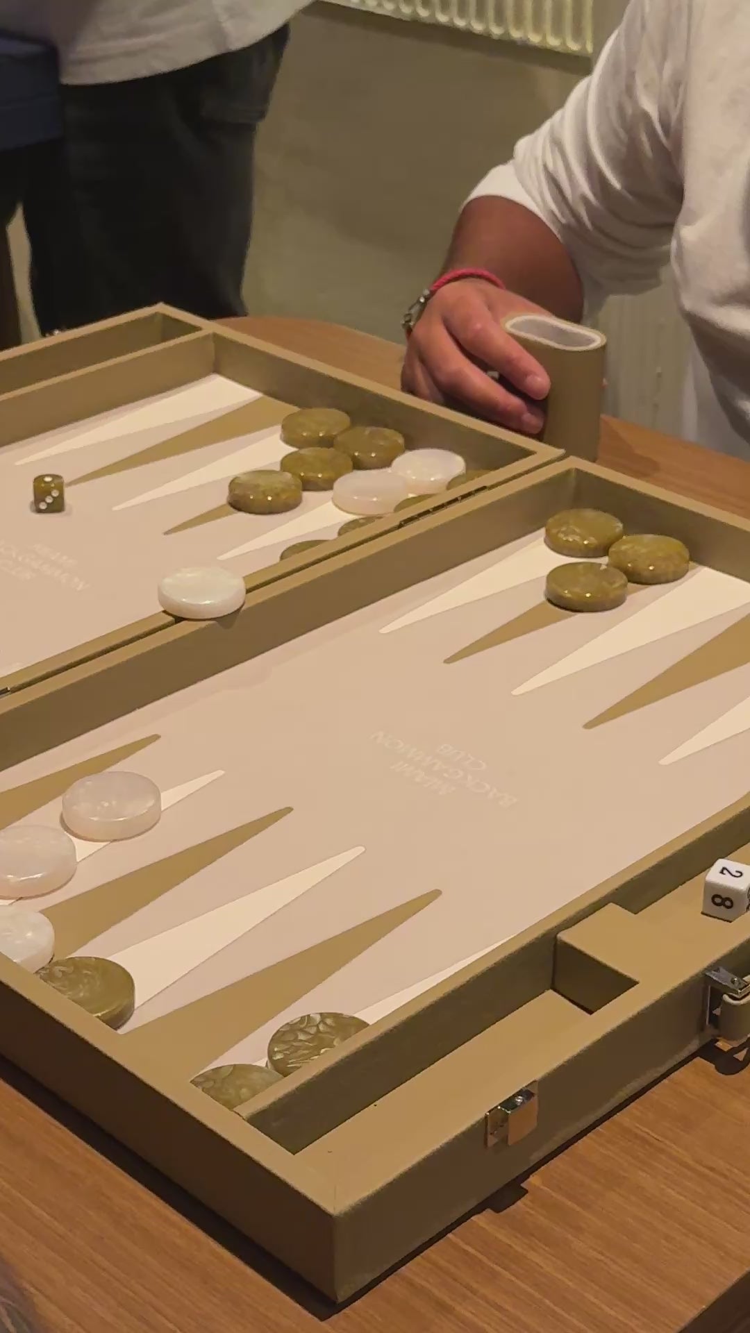 two men playing backgammon with the miami backgammon club's beige board