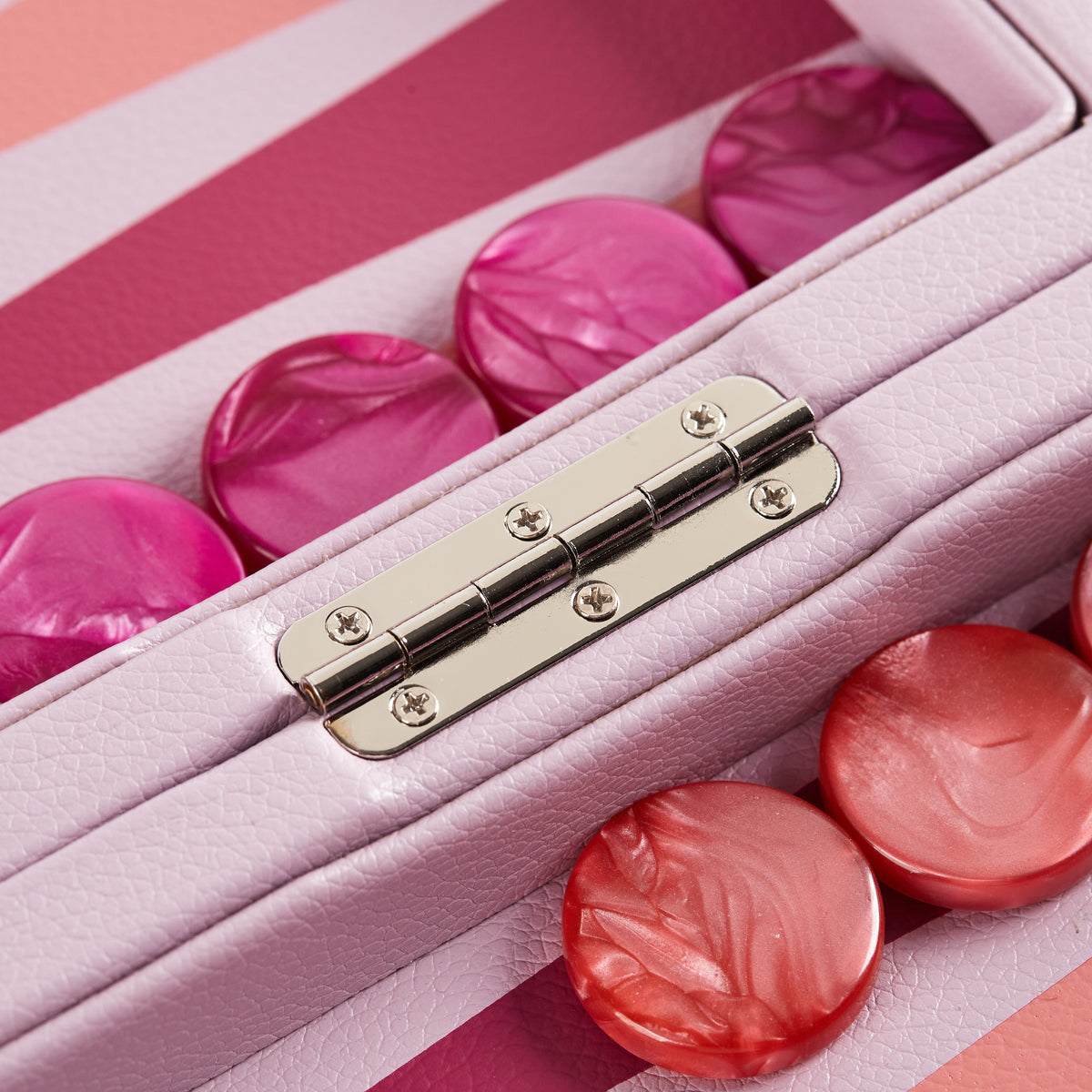 Close-up of coral and fuchsia pearlescent checkers either side of the hinge